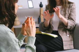 Mulheres brancas estão conversando em uma sessão terapêutica em uma sala fechada, em que a psicóloga fala como controlar vício em apostas